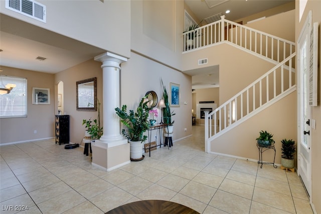 tiled foyer entrance featuring a notable chandelier, decorative columns, and a high ceiling