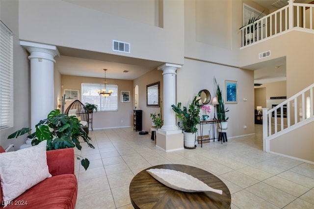 tiled entryway with ornate columns, a high ceiling, and a chandelier