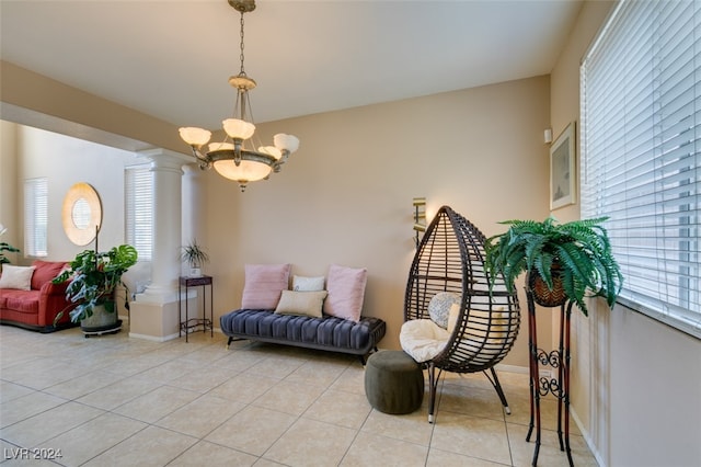 living area featuring light tile patterned floors, a notable chandelier, and ornate columns