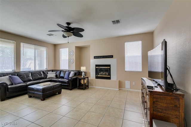 tiled living room with ceiling fan, a tiled fireplace, and plenty of natural light