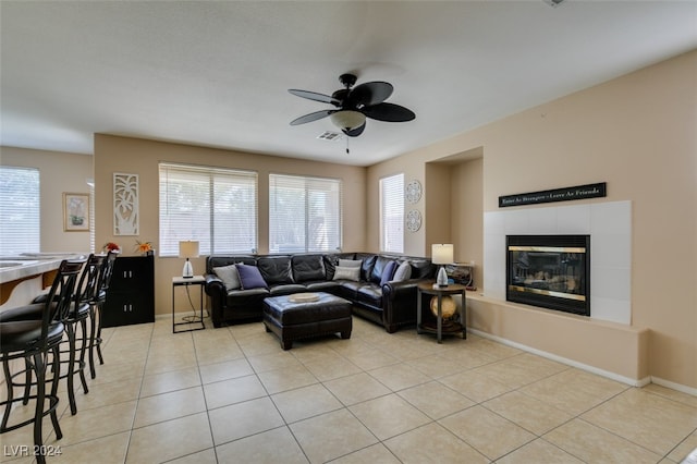 tiled living room featuring ceiling fan and a tile fireplace