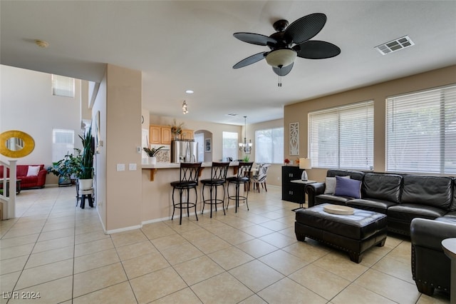 tiled living room featuring ceiling fan with notable chandelier