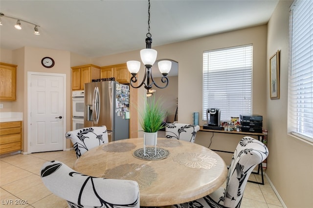 tiled dining area with a wealth of natural light and an inviting chandelier