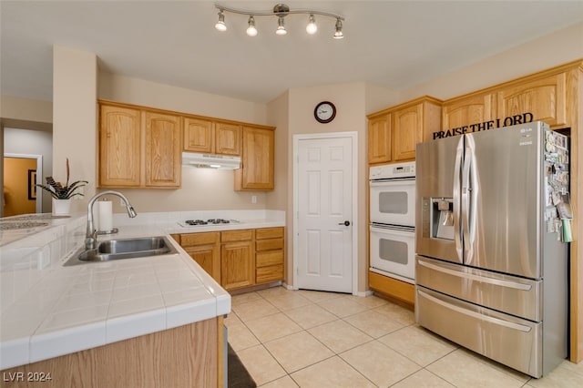 kitchen with white appliances, sink, tile countertops, kitchen peninsula, and light tile patterned floors