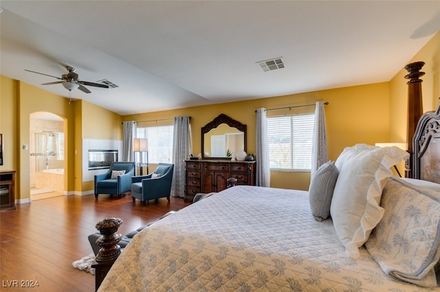 bedroom with ceiling fan, ensuite bathroom, multiple windows, and hardwood / wood-style flooring