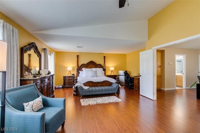 bedroom with ensuite bathroom, lofted ceiling, hardwood / wood-style floors, and multiple windows