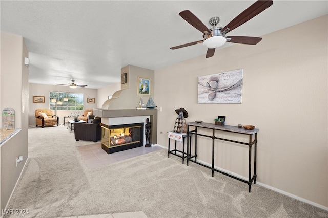 carpeted living room with a multi sided fireplace and ceiling fan