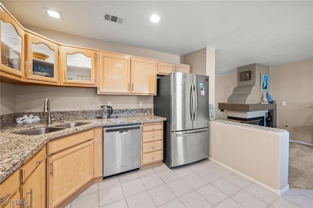 kitchen featuring light stone countertops, light brown cabinets, sink, appliances with stainless steel finishes, and light tile patterned floors