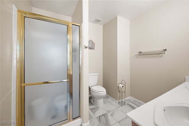 bathroom featuring vanity, a shower with shower door, and toilet