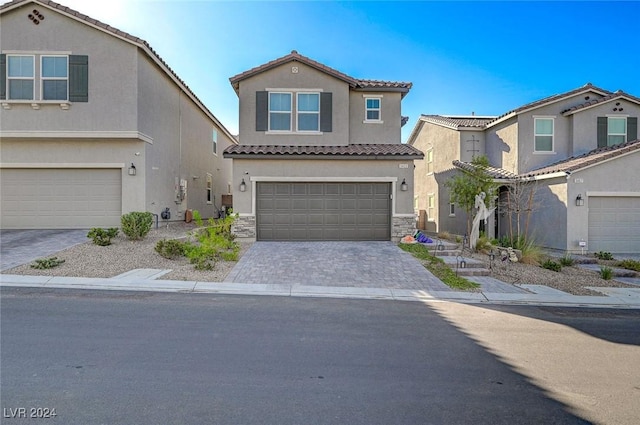 mediterranean / spanish-style home with stucco siding, a tiled roof, decorative driveway, and an attached garage