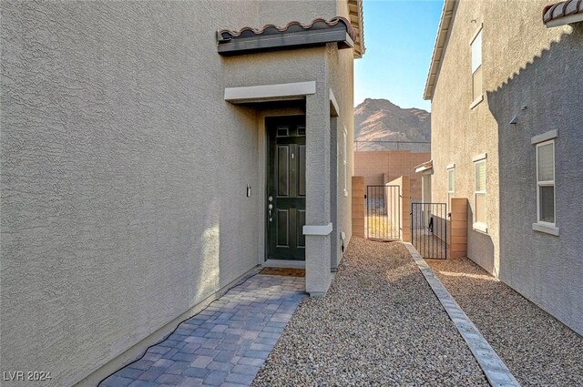 doorway to property with stucco siding, fence, a tile roof, and a gate