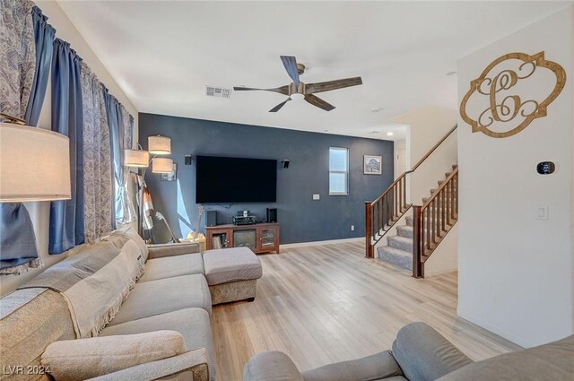 living room with baseboards, stairway, visible vents, ceiling fan, and light wood finished floors