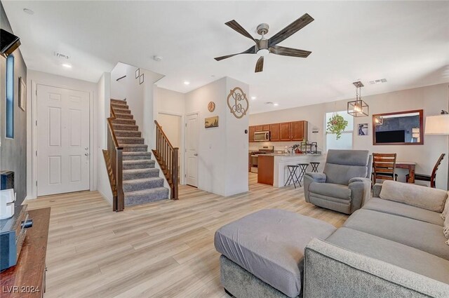 living room with light wood-style floors, a ceiling fan, visible vents, recessed lighting, and stairs