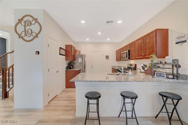 kitchen featuring stainless steel appliances, a peninsula, visible vents, and a kitchen bar