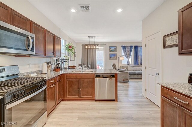 kitchen featuring a peninsula, light wood-style floors, visible vents, appliances with stainless steel finishes, and a sink