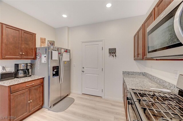 kitchen with recessed lighting, stainless steel appliances, brown cabinets, light wood finished floors, and baseboards