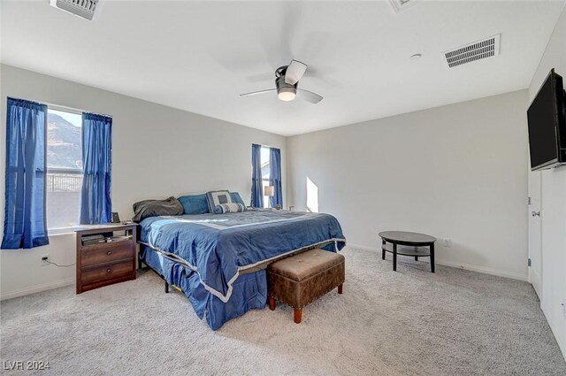 carpeted bedroom with a ceiling fan, multiple windows, and visible vents