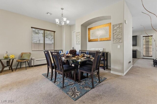 carpeted dining space featuring a notable chandelier