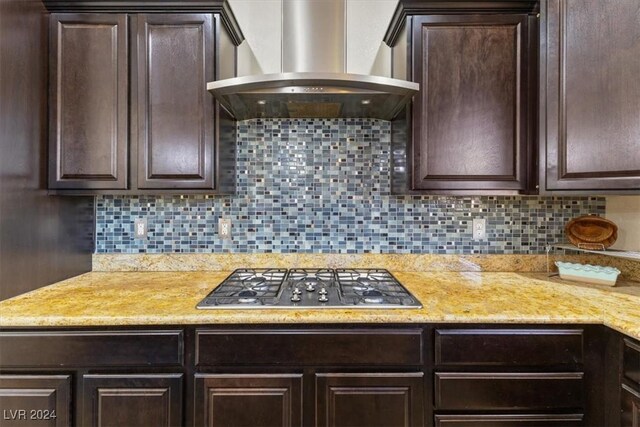 kitchen featuring dark brown cabinetry, wall chimney exhaust hood, and stainless steel gas cooktop