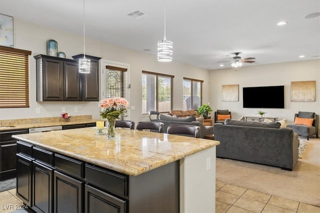 kitchen featuring light stone countertops, ceiling fan, a center island, hanging light fixtures, and light tile patterned floors