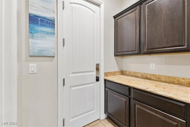 interior space featuring dark brown cabinets, light stone counters, and light tile patterned floors