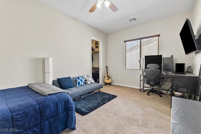 bedroom featuring ceiling fan, light colored carpet, and a walk in closet