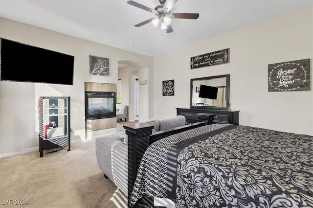 carpeted bedroom with a tiled fireplace and ceiling fan