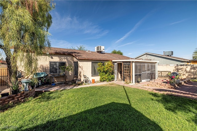 back of property featuring a yard, a sunroom, cooling unit, and a patio