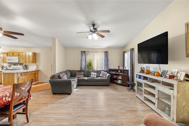 living room featuring vaulted ceiling, light wood-type flooring, and ceiling fan