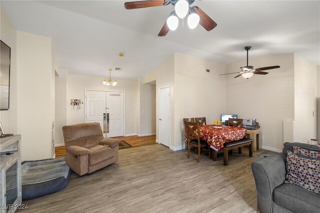 living room featuring ceiling fan with notable chandelier and light hardwood / wood-style floors