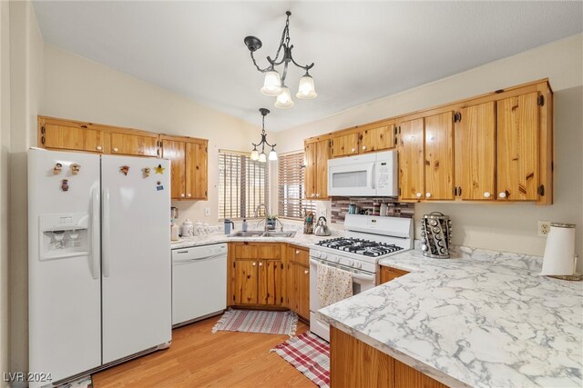 kitchen featuring sink, white appliances, decorative light fixtures, light hardwood / wood-style flooring, and a notable chandelier