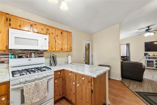 kitchen featuring ceiling fan, lofted ceiling, kitchen peninsula, white appliances, and light hardwood / wood-style flooring