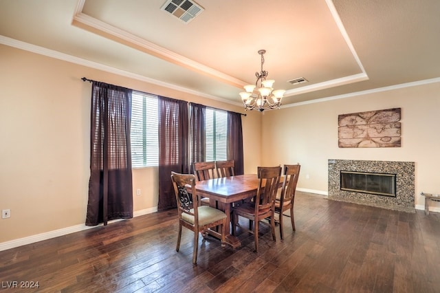 dining room featuring dark wood-type flooring, a raised ceiling, visible vents, and a fireplace