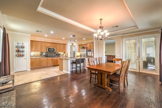 dining space with light wood-style floors, visible vents, and a raised ceiling