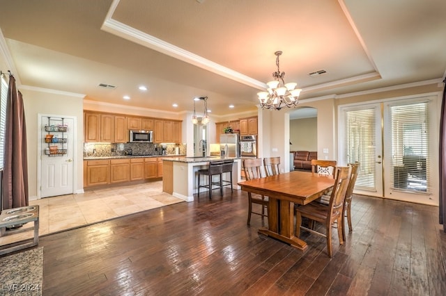 10909 Bramante Dr, Las Vegas, NV 89141 - dining space with a notable chandelier, a tray ceiling, ornamental molding, visible vents, and light wood-style floors