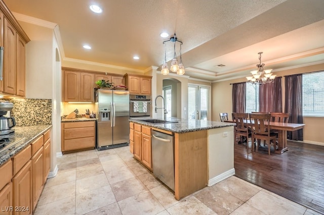 kitchen with stainless steel appliances, an island with sink, a sink, and pendant lighting