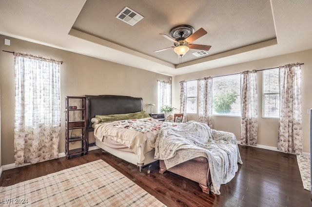 bedroom featuring visible vents, a tray ceiling, and dark wood-type flooring