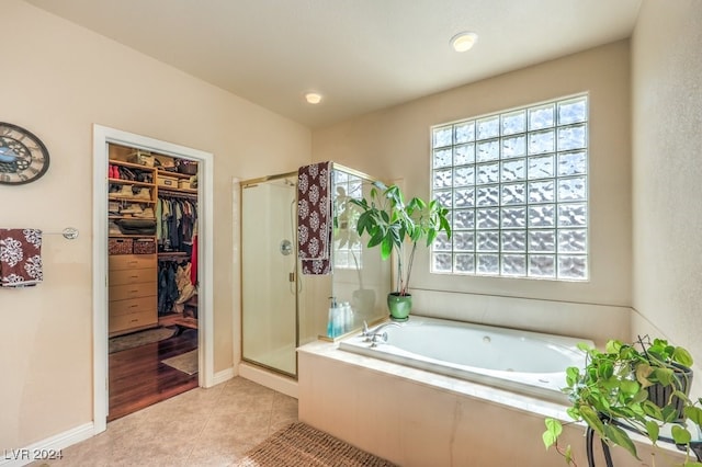 full bath with a stall shower, a walk in closet, a garden tub, and tile patterned floors