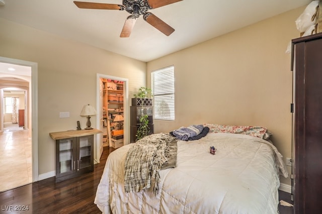 bedroom featuring arched walkways, dark wood-style flooring, multiple windows, and baseboards