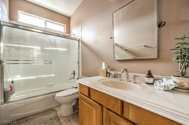 bathroom with a textured wall, toilet, and bath / shower combo with glass door