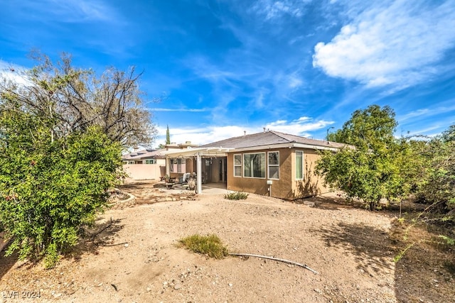 rear view of house featuring a patio, fence, and stucco siding