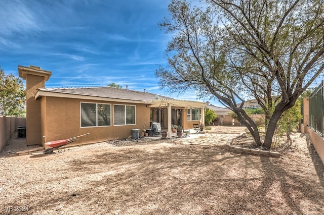 rear view of house with central air condition unit, stucco siding, a patio area, a pergola, and a fenced backyard