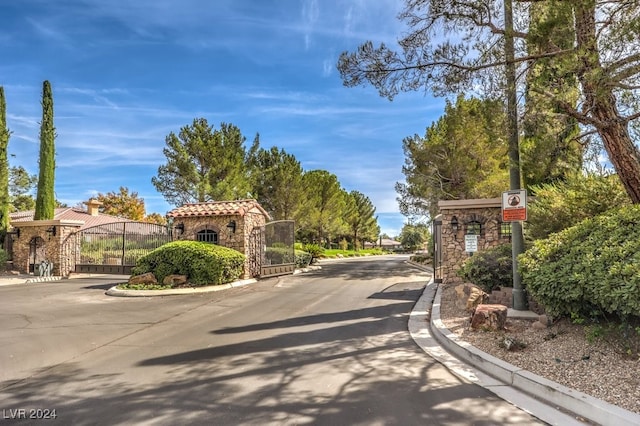 view of road with curbs, a gated entry, and a gate