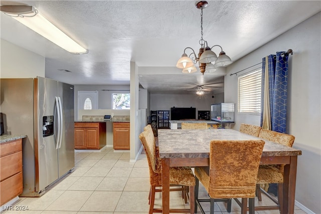 dining area with a textured ceiling, ceiling fan with notable chandelier, plenty of natural light, and light tile patterned floors