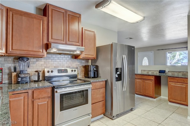 kitchen with dark stone countertops, stainless steel appliances, light tile patterned floors, and decorative backsplash