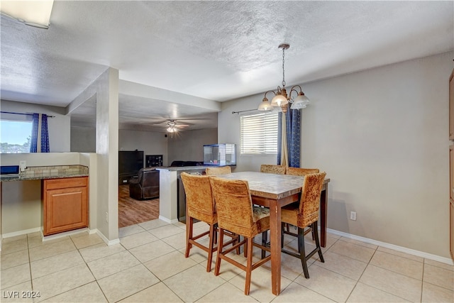 dining space featuring ceiling fan with notable chandelier, plenty of natural light, and a textured ceiling