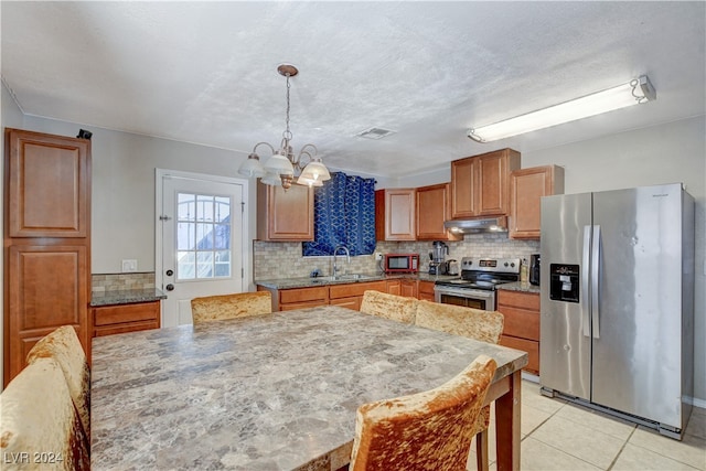 kitchen featuring hanging light fixtures, sink, backsplash, appliances with stainless steel finishes, and an inviting chandelier