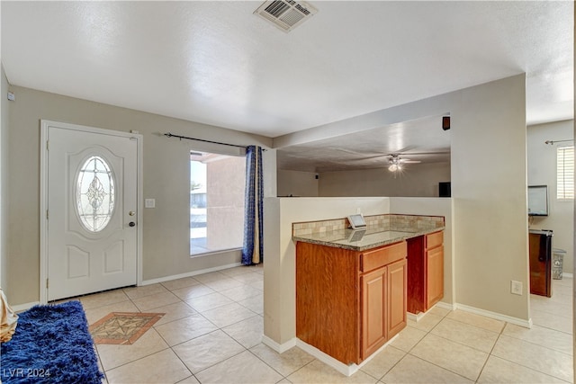 kitchen featuring stone countertops, ceiling fan, light tile patterned floors, and a textured ceiling