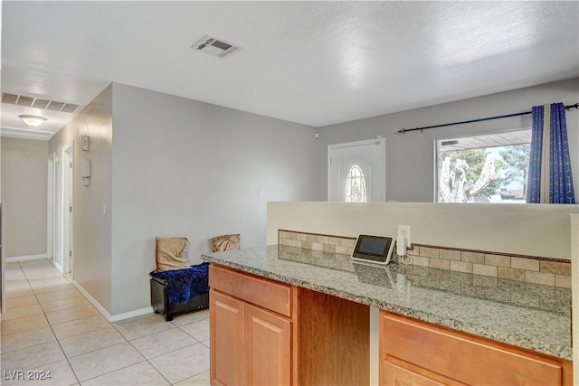 kitchen featuring light stone countertops, light tile patterned floors, and a textured ceiling