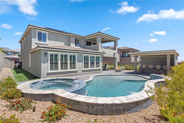 back of house featuring a swimming pool with hot tub and a patio